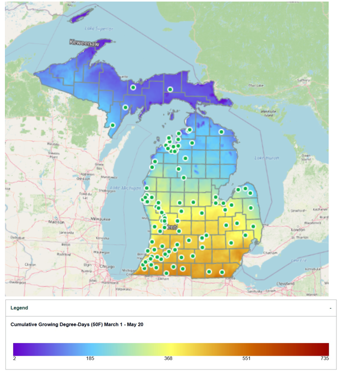 Map of Michigan showing cumulative Growing Degree-Days (base 50&deg;F) from March 1 to May 20, with color shading ranging from purple and blue in northern regions to yellow, orange, and red in southern regions to indicate increasing heat accumulation. Green-and-white dots mark monitoring station locations across the state, and a legend at the bottom displays the degree-day scale from 2 to 735.